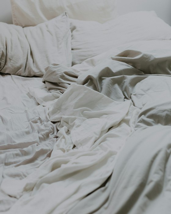 Cama com edredom branco amarrotado e sem volume antes da lavagem