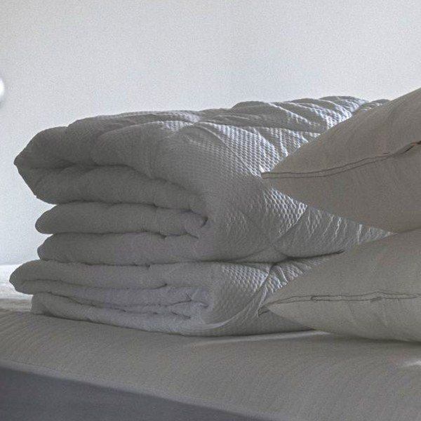 Cobertor e edredom brancos dobrados sobre a cama